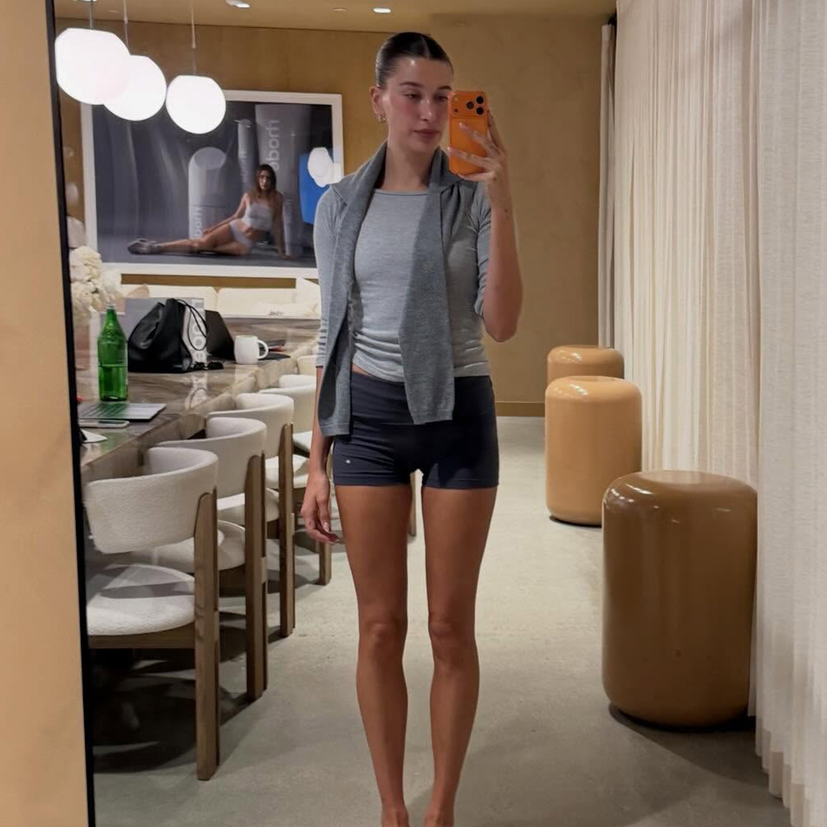 Hailey bieber wears a gray shirt and black shorts.