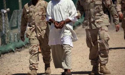 A detainee flanked by U.S. soldiers at Guantanamo Bay