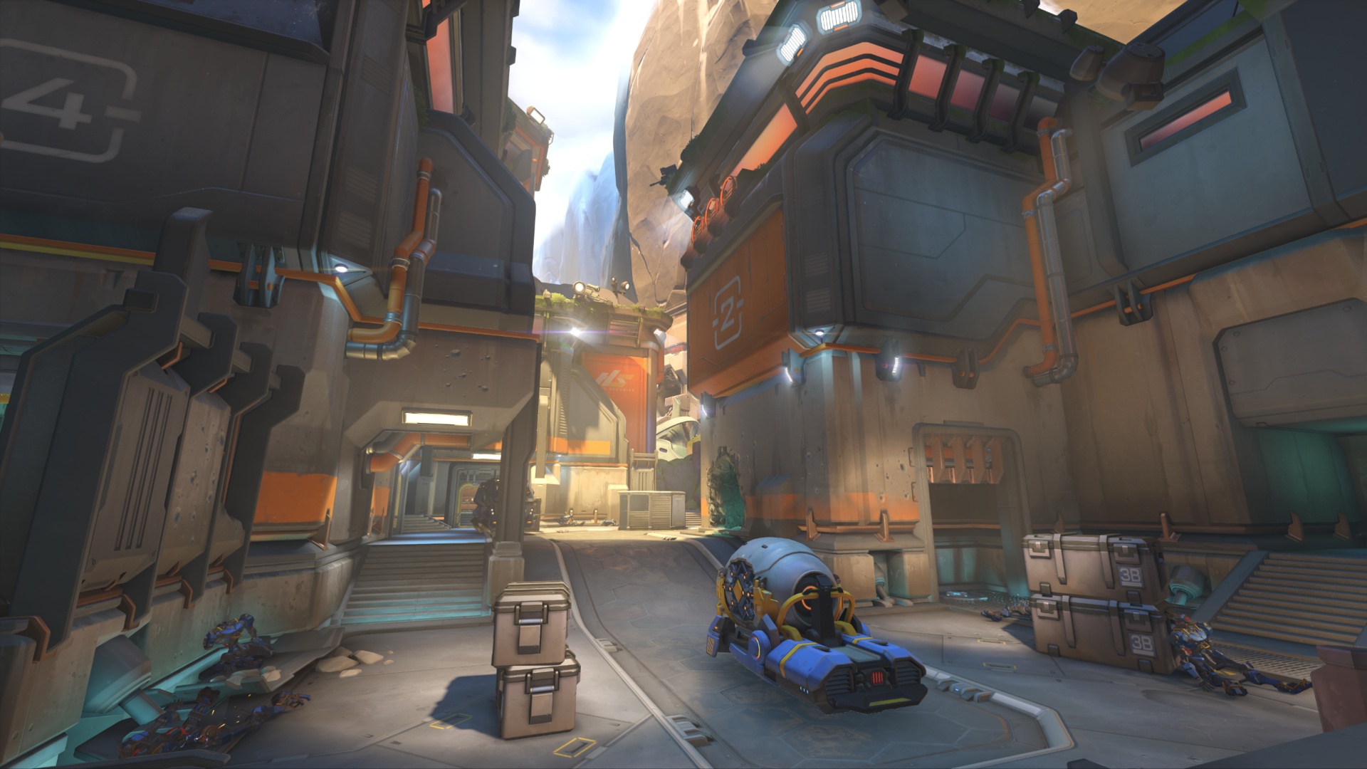 A fallen blue-armored figure lies in a futuristic industrial alley, surrounded by crates and pipes beneath towering metal buildings and warm light.