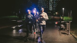 Group of runners in a city at night wearing headtorches