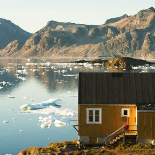 steel cabin house in yellow and grey near lake with mountains