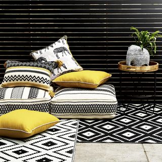 monochrome rug with cushions and plant