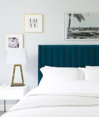 Green fluted velvet green headboard in bedroom with white pillows in front and a bedside table and bedside lamp