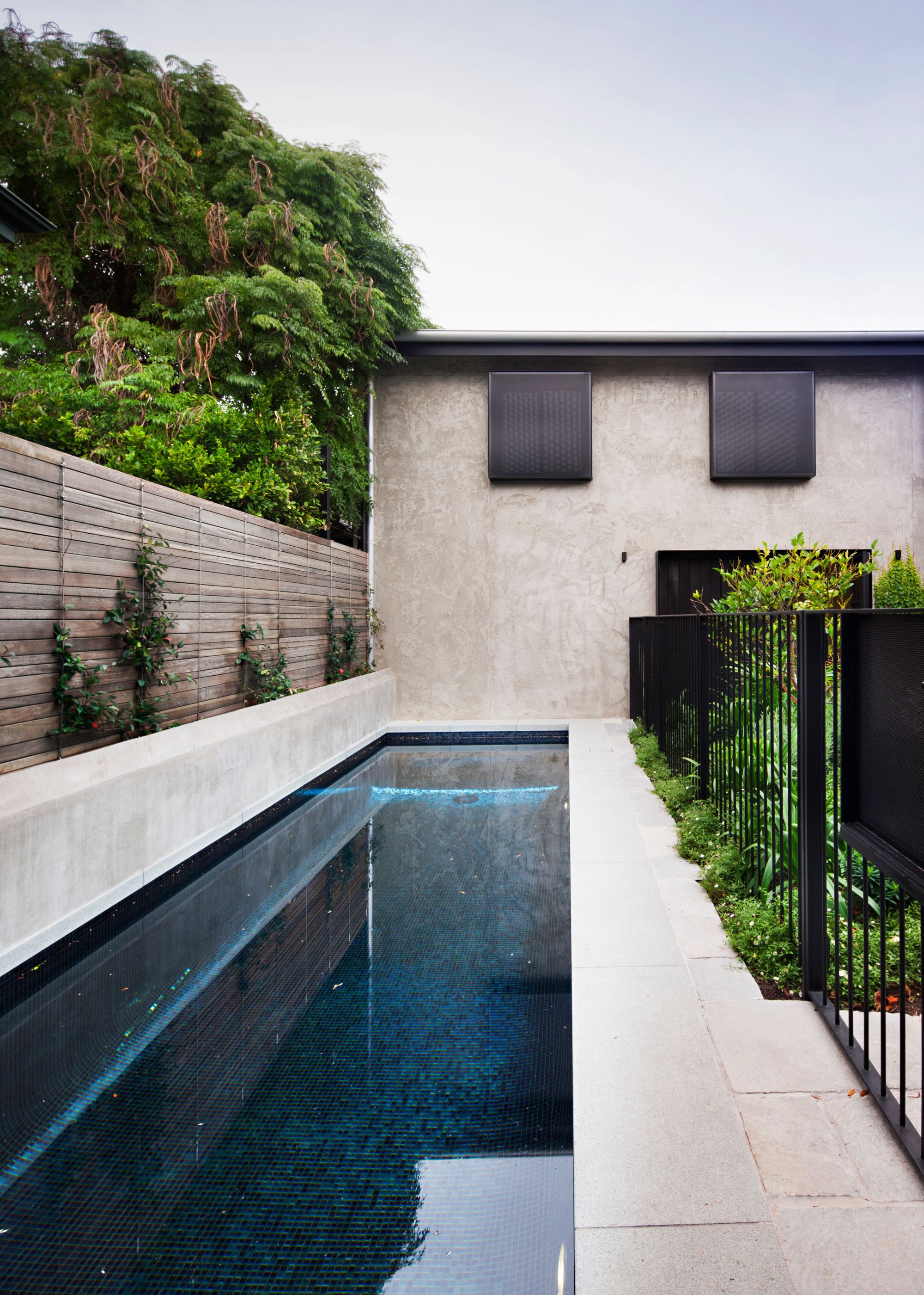 A narrow small pool surrounded by concrete flooring and walls