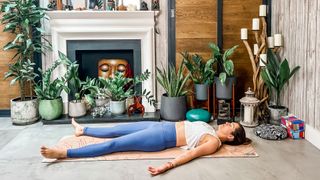 Woman lying down in Corpse yoga pose.