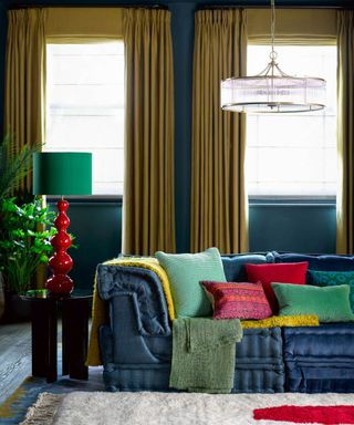 A modern living room idea with primary colored decor and Pooky Larger Wobster lamp in Red, £149, with 35 cm drum shade in Emerald dupion silk, £74, and Athena chandelier, £305