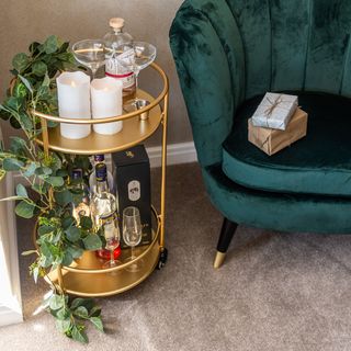 green arm chair and golden trolley and drinks