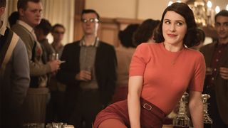 Mrs Maisel sitter på ett bord och ser nöjd ut.