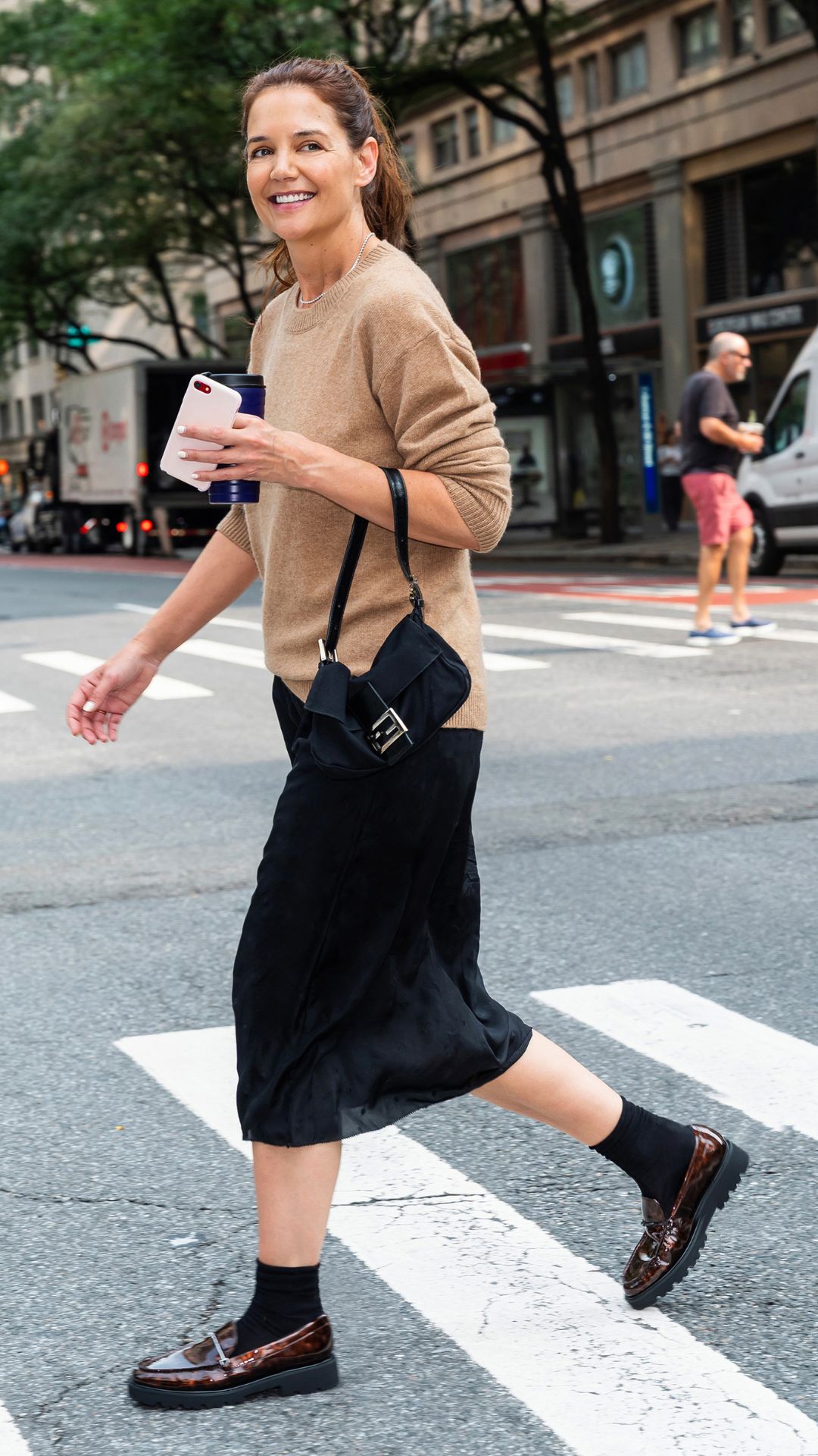 Katie Holmes wearing midi skirt, knit jumper and loafers on 23 September, 2025