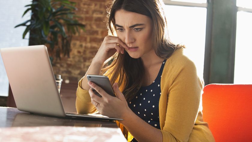 a woman looks at her phone with a stressed expression