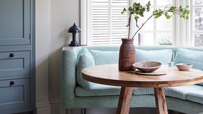 blue couch, wooden table and cabinetry by window