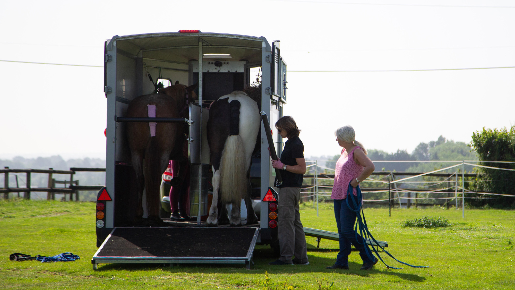 Two women securing horsebox with horses on board early in the morning to avoid travelling in hot weather