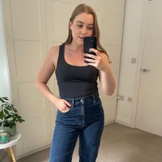 Woman wears grey tank top and blue jeans