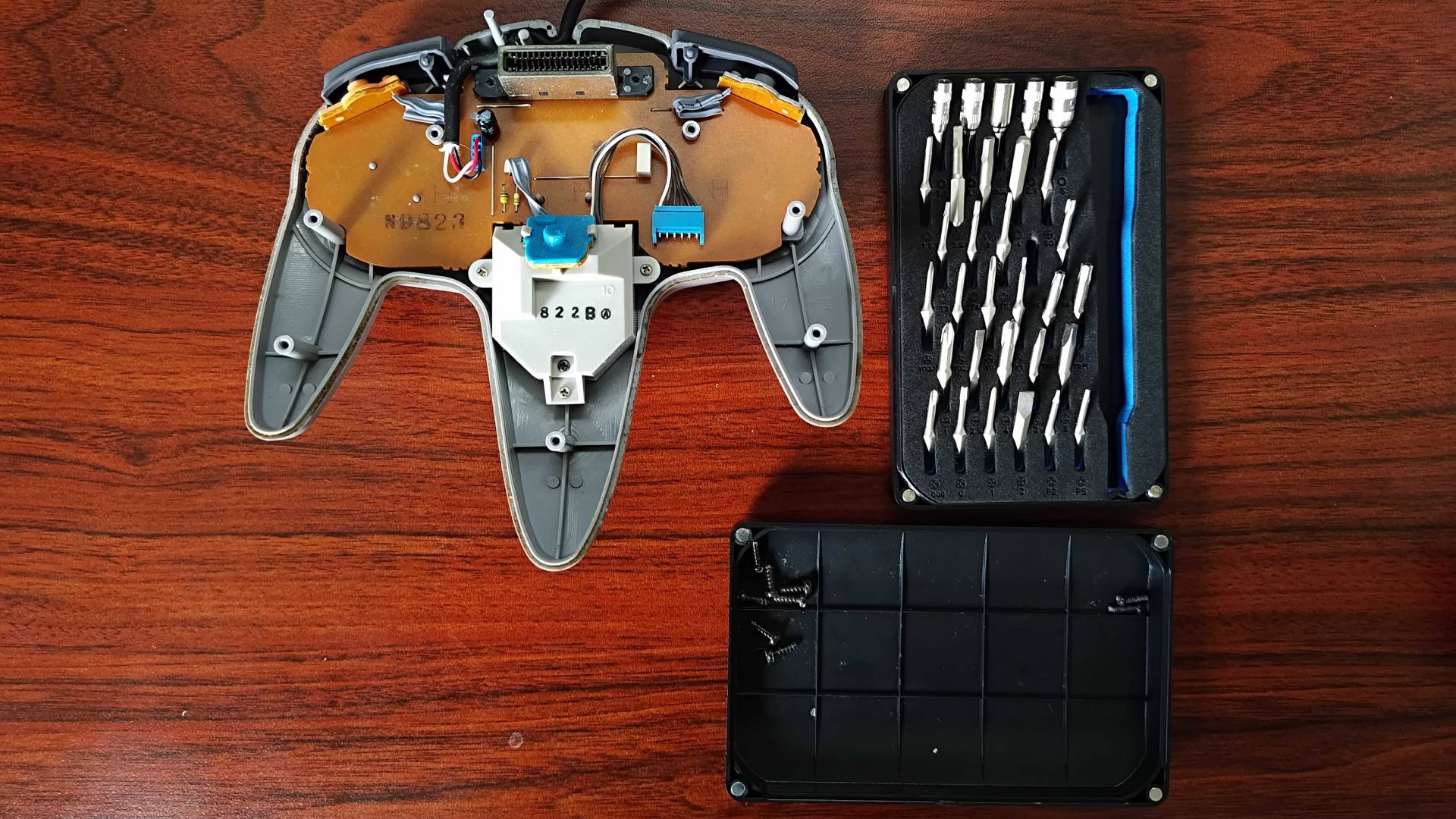 N64 controller with back shell removed next to iFixit screwdriver set.