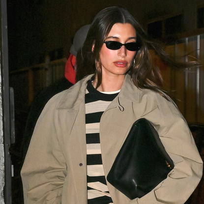 Hailey Bieber is spotted in NYC wearing a trench coat and an oversized clutch.
