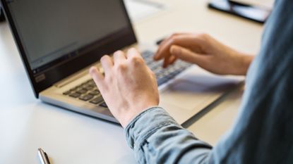 Hands type on a laptop.