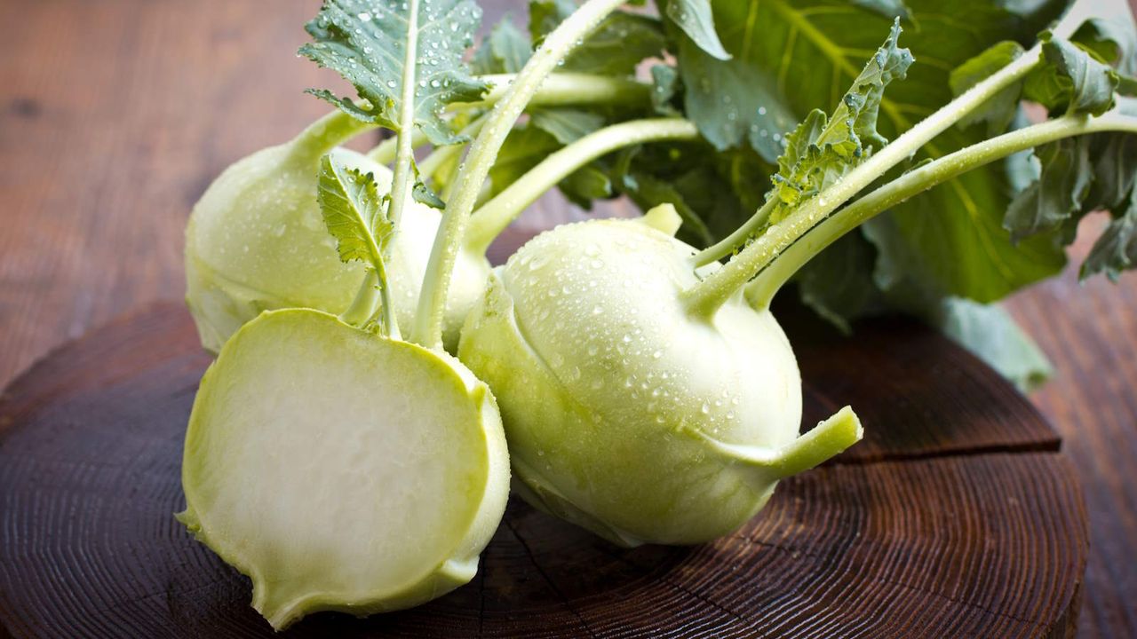 Fresh harvested kohlrabi whole and sliced on a wooden board