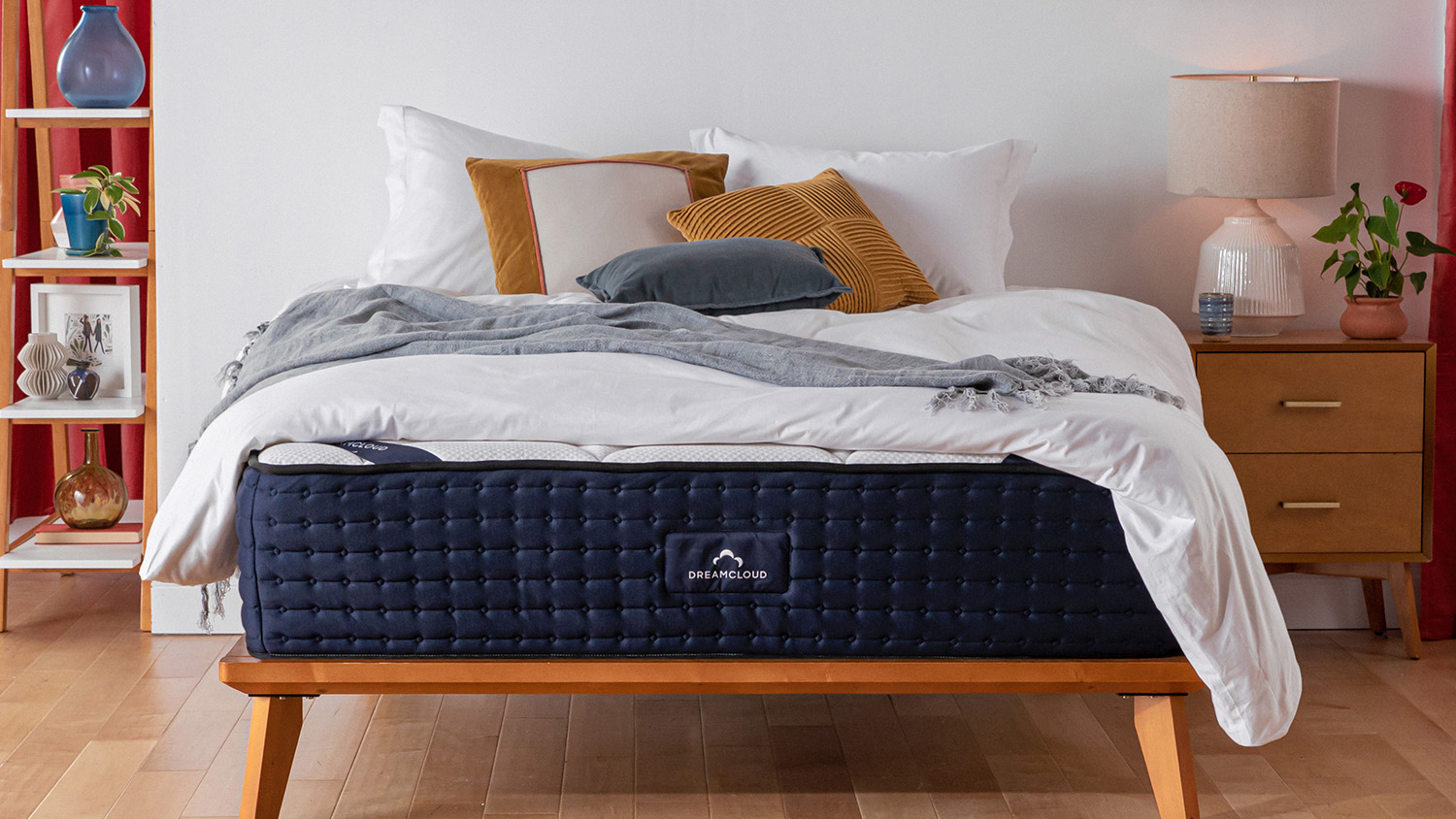 DreamCloud Luxury Hybrid Mattress diletakkan di atas bingkai tempat tidur kayu di kamar tidur berwarna putih