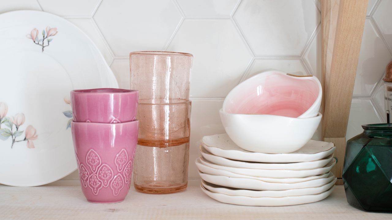 Kitchen shelf lined with pink accessories including glasses and bowls