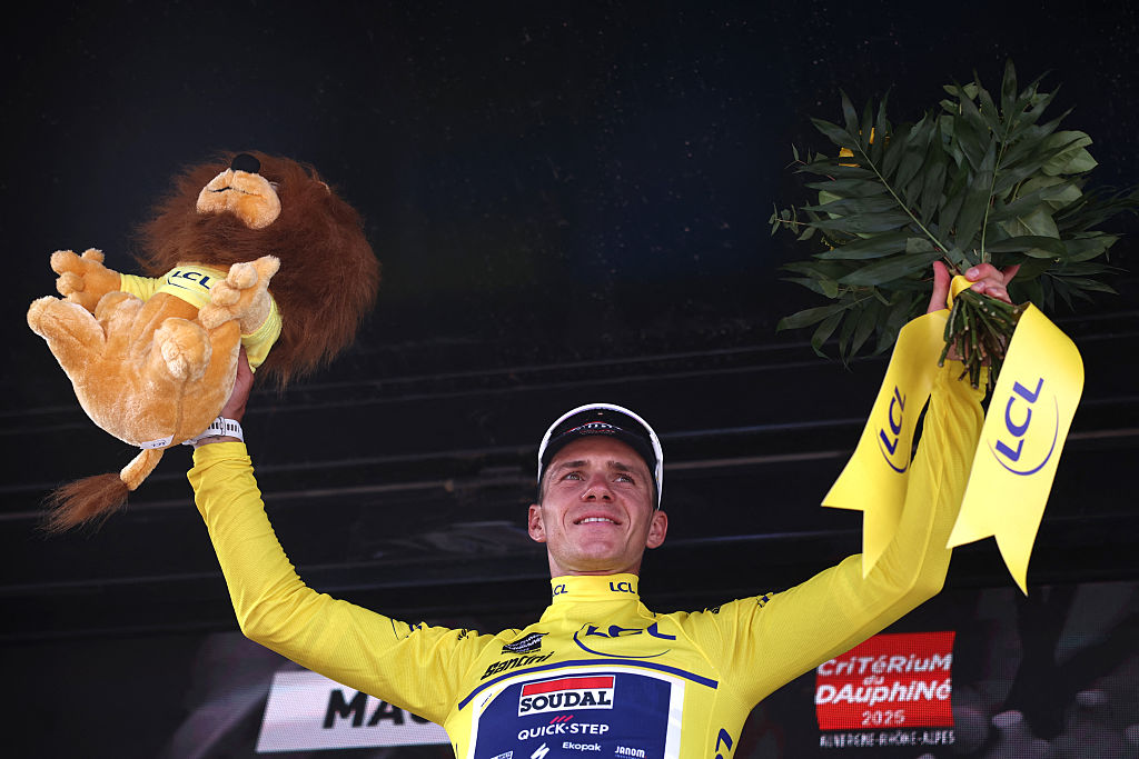 Soudal Quick-Step's Belgian rider Remco Evenepoel wearing the overall leader's yellow jersey celebrates on the podium of the 5th stage of the 77th edition of the Criterium du Dauphine cycling race, 183 km between Saint-Priest and Mâcon, on June 12, 2025. (Photo by Anne-Christine POUJOULAT / AFP) (Photo by ANNE-CHRISTINE POUJOULAT/AFP via Getty Images)