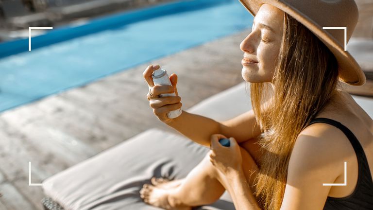 person sat beside a swimming pool wearing a sun hat and spritzing face demonstrating how to keep cool in summer