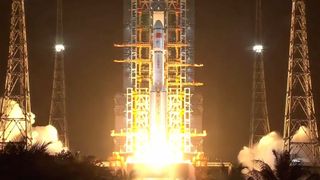 a white rocket rises off its launch pad at night.