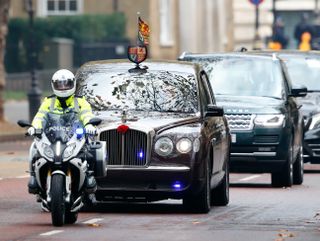 Queen Elizabeth II travels in her chauffeur driven Bentley car (with a motorcycle outrider of the Metropolitan Police Special Escort Group) after attending the National Service of Remembrance at The Cenotaph on November 8, 2020