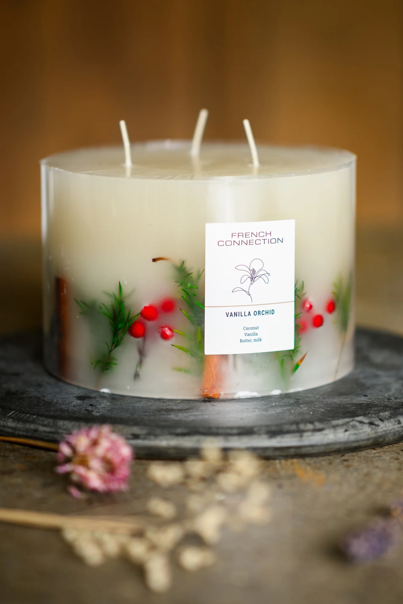 A white inclusion candle with red berries and fir sprigs