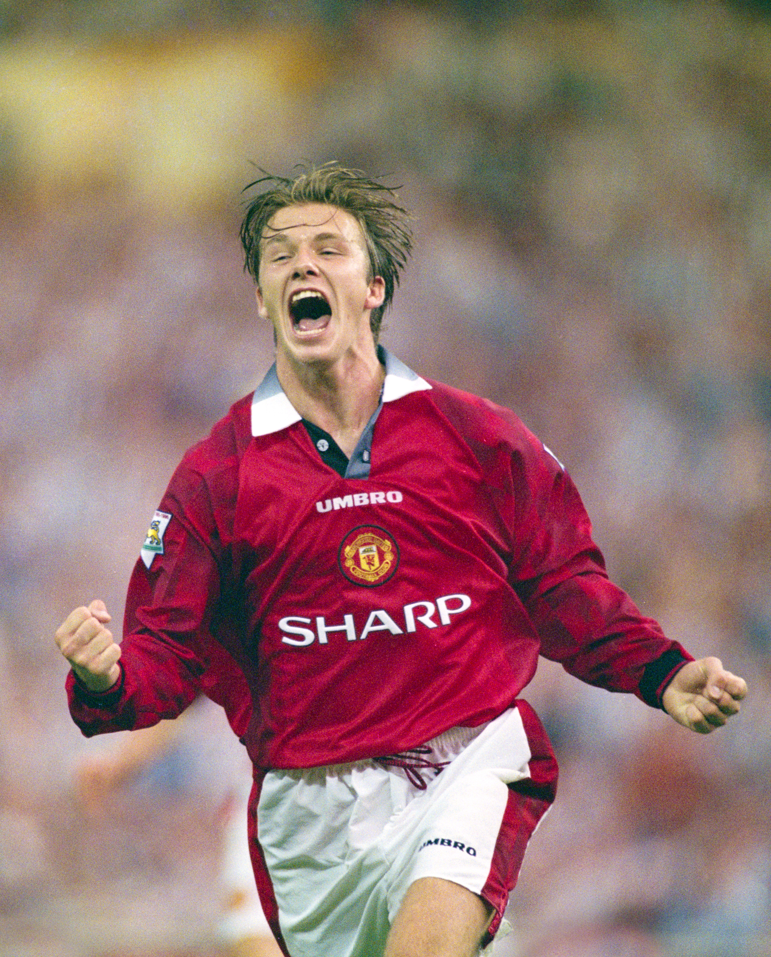 Sir David Beckham in a red Manchester United shirt playing football