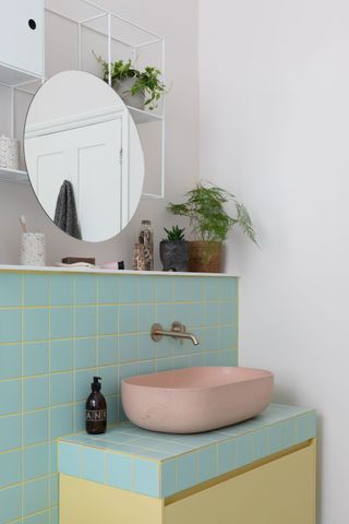 a bathroom with a yellow grout, turquoise tile and pink basin
