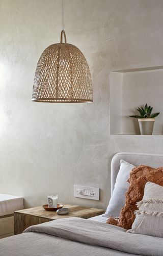 A bedroom with a cane hanging lamp