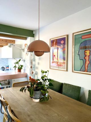 A pair of colorful prints next to a dining table and pendant