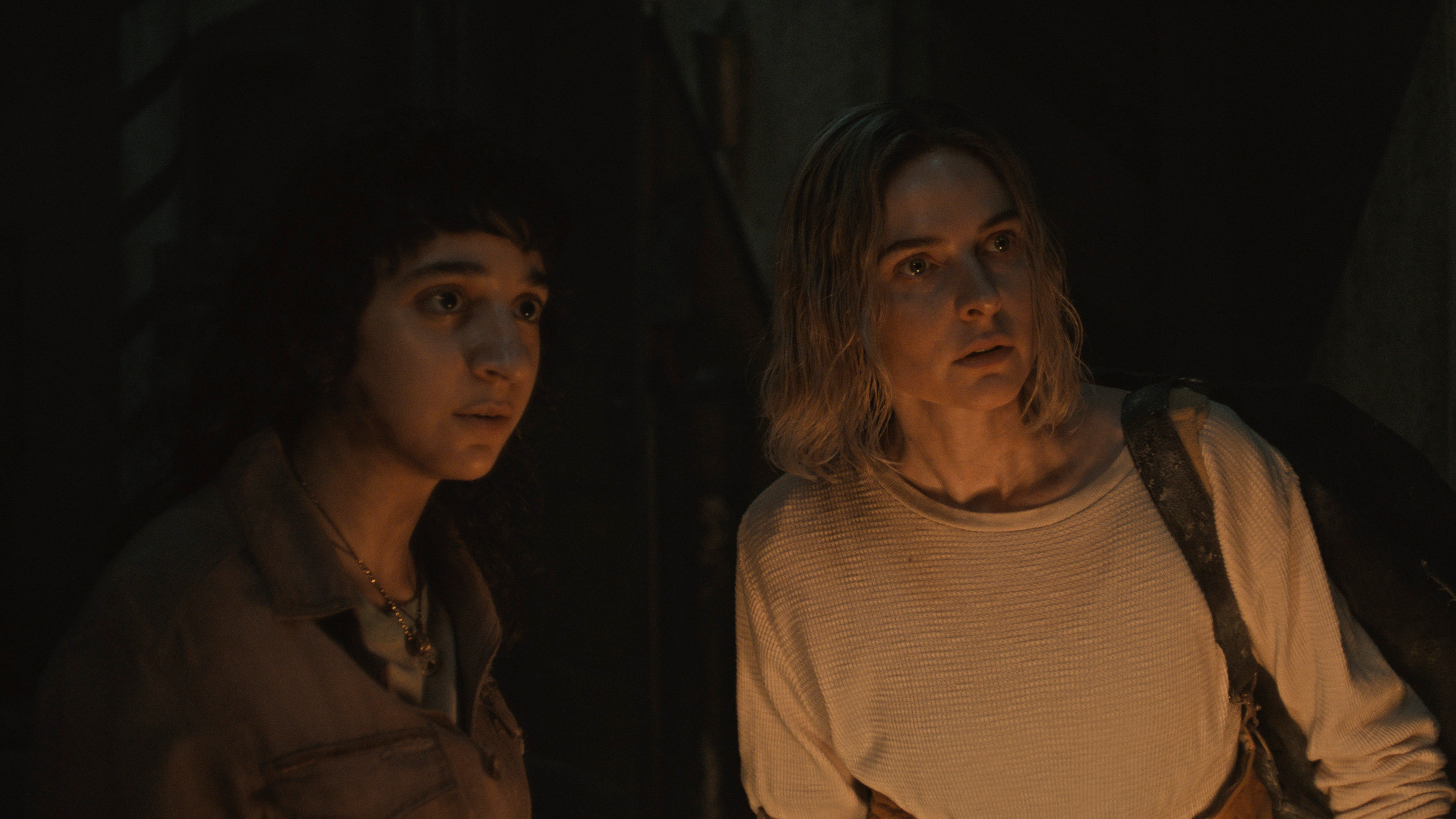 Two women investigate a darkened chamber