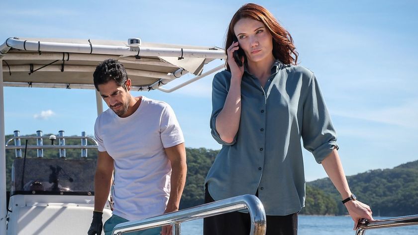 Mack on the phone standing by Greg on a boat