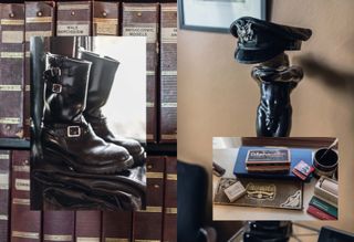 Left image: pair of male black leather buckle boots, sat on black folded leather, backdrop books on shelves Right image: male erotic black ornament with black leather cap on top, neutral wall, bottom of black picture frame, central image of a desk with small boxes of crayons, and artist tools