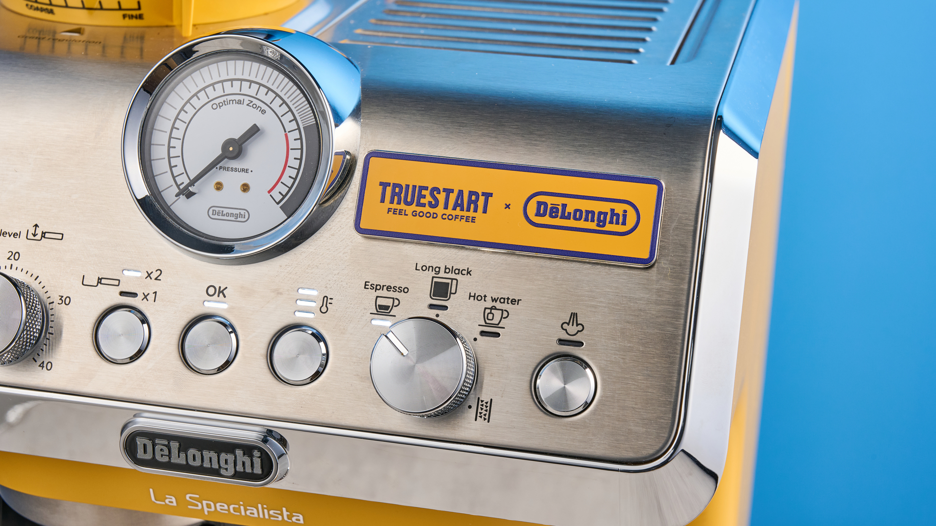the de'longhi la specialista arte evo special edition truestart edition, with yellow body, showing the espresso machine attachments like tamper, tamping collar, grinder, and control buttons