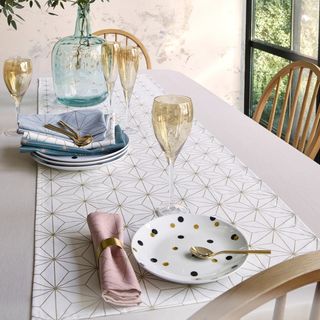Christmas table runner in white and gold stars on a table from La Redoute with a champagne glass