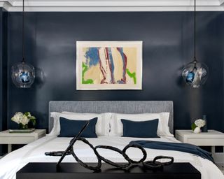 A bedroom TV idea with TV concealed in a bed end unit topped with contemporary abstract sculpture