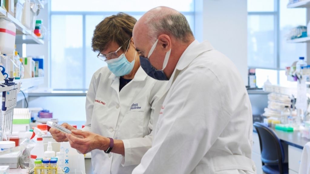 katalin kariko and drew weissman are pictured working at a lab bench and wearing surgical masks