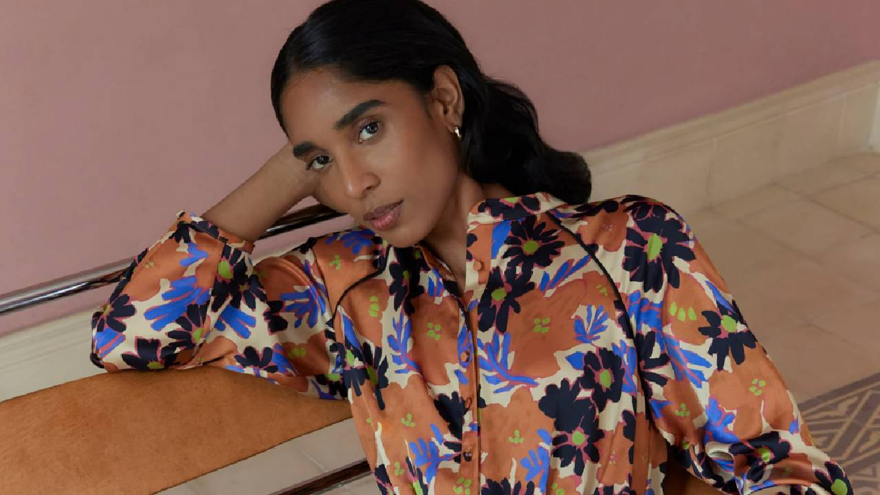 A female model wearing an orange, brown, and blue floral blouse from Hobbs.