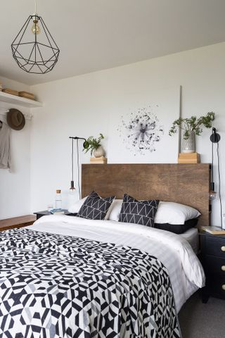 Wooden double bed with monochrome sheets, dangling bedside lamps and house plant decoration