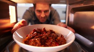 Man putting meal into microwave