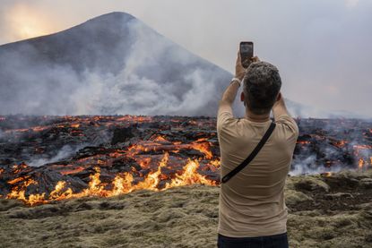 A tourist takes a picture of Mount Fagradalsfjall after its eruption