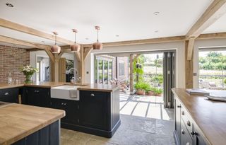 kitchen in oak framed extension with folder doors and blue peninsula cabinetry