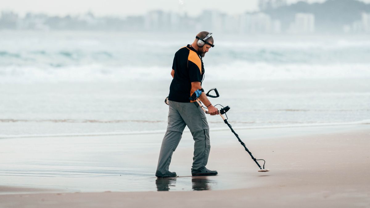 Man with a metal detector on the beach