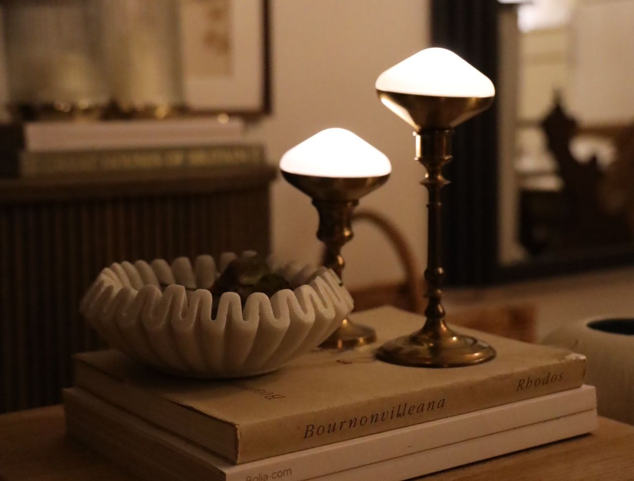 Two diamond shaped puck lights in brass candle holders placed on a stack of books