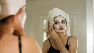 A woman applying a clay mask