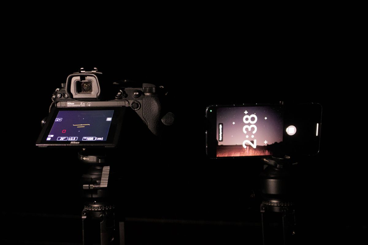 Pixel phone and Nikon mirrorless camera side by side mounted to tripods at night, with the astrophotography mode active on the Pixel