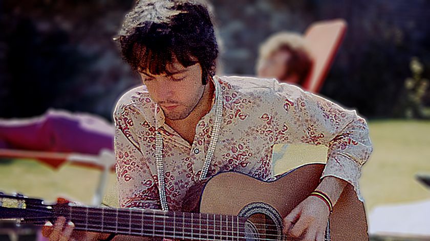 Paul McCartney from the Beatles plays an acoustic guitar while John Lennon (1940-1980) sunbathes behind in London, summer 1967. 