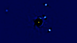 Exoplanets circling around the star HR8799 in an animation still.
